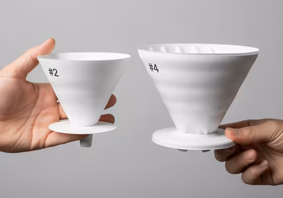 A #2 coffee filter held next to a larger #4 coffee filter for a clear size comparison.