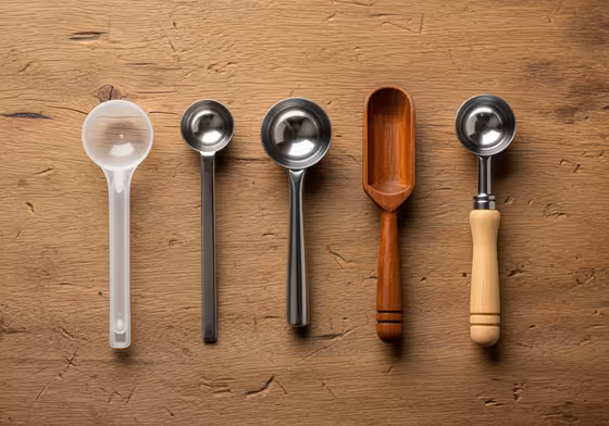 A collection of different coffee scoops of various sizes and materials, illustrating their lack of standardization.