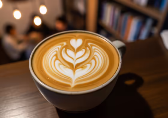 A perfectly made latte in a ceramic cup with intricate latte art on top.