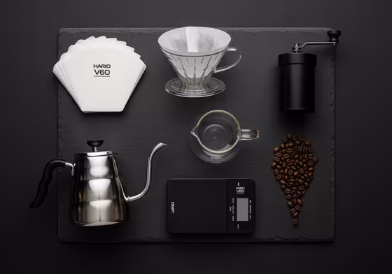 A flat lay photograph of all the equipment needed for V60 pour-over coffee, neatly arranged.