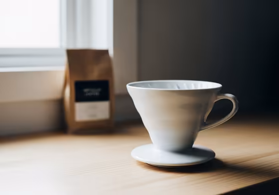 A white Hario V60 ceramic coffee dripper sitting on a kitchen counter.