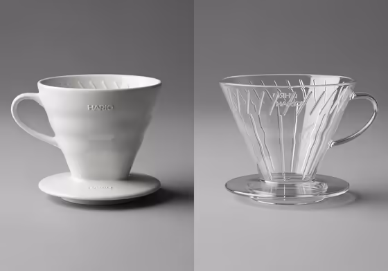 A photo showing a white ceramic Hario V60 next to a clear plastic Hario V60 for comparison.