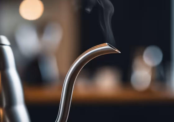 A detailed close-up of the Hario V60 Buono's gooseneck spout, with steam rising from the tip.
