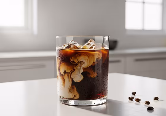 A tall glass of refreshing cold brew coffee concentrate mixed with milk and ice, showing its rich, dark color.
